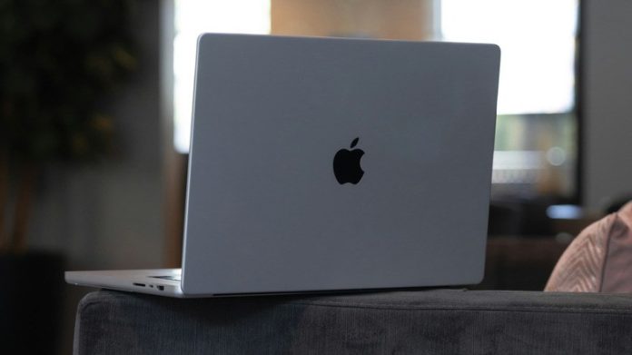 An open MacBook on the arm of a couch
