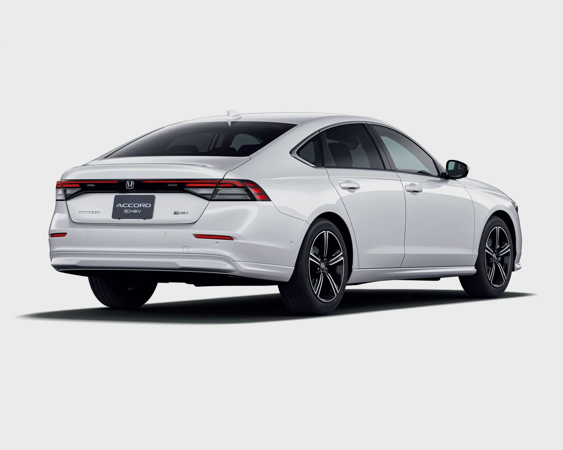 White Honda Accord e:HEV hybrid sedan rear view with black alloy wheels on a white background.