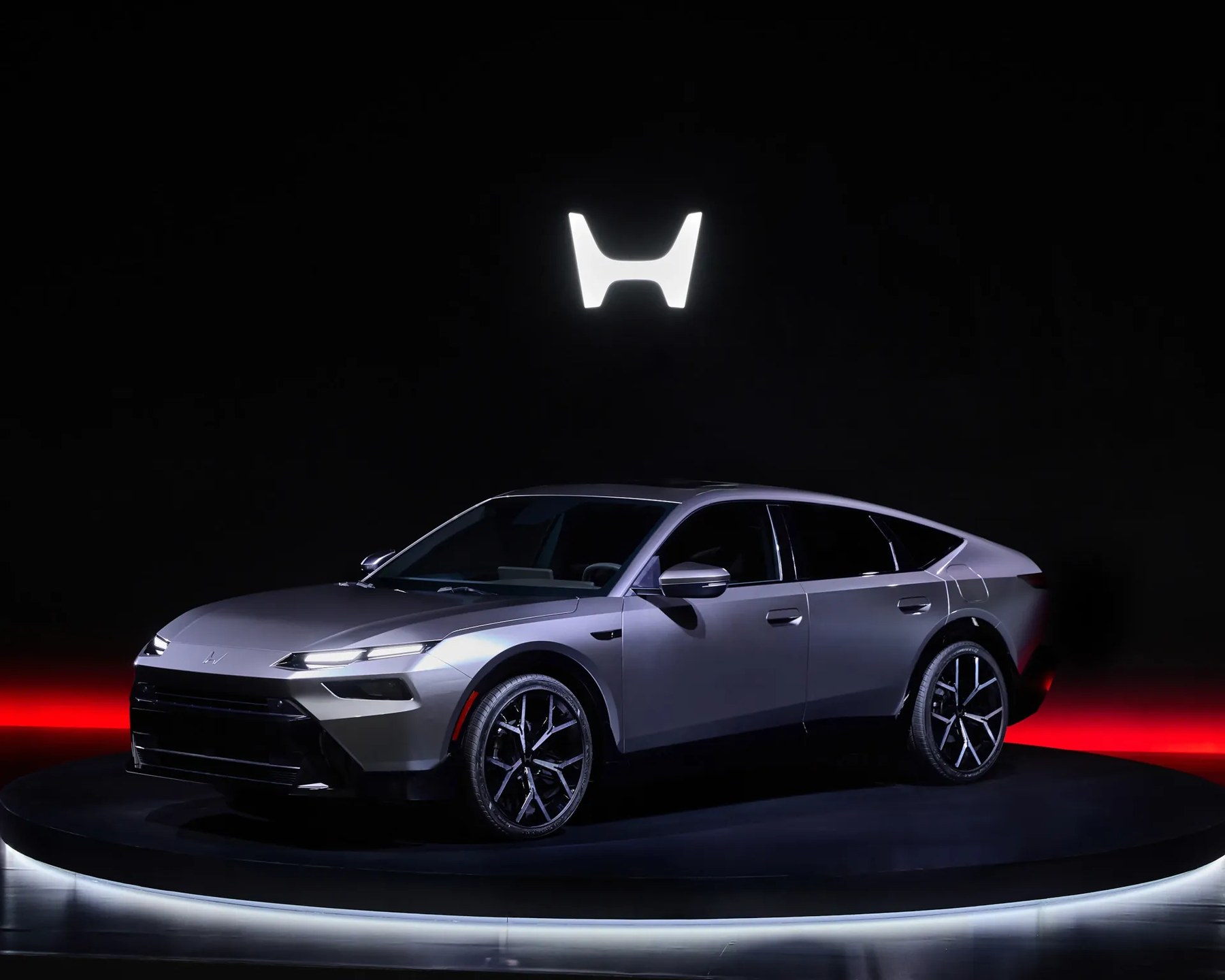 Silver Honda electric SUV on a circular platform with illuminated Honda logo above.