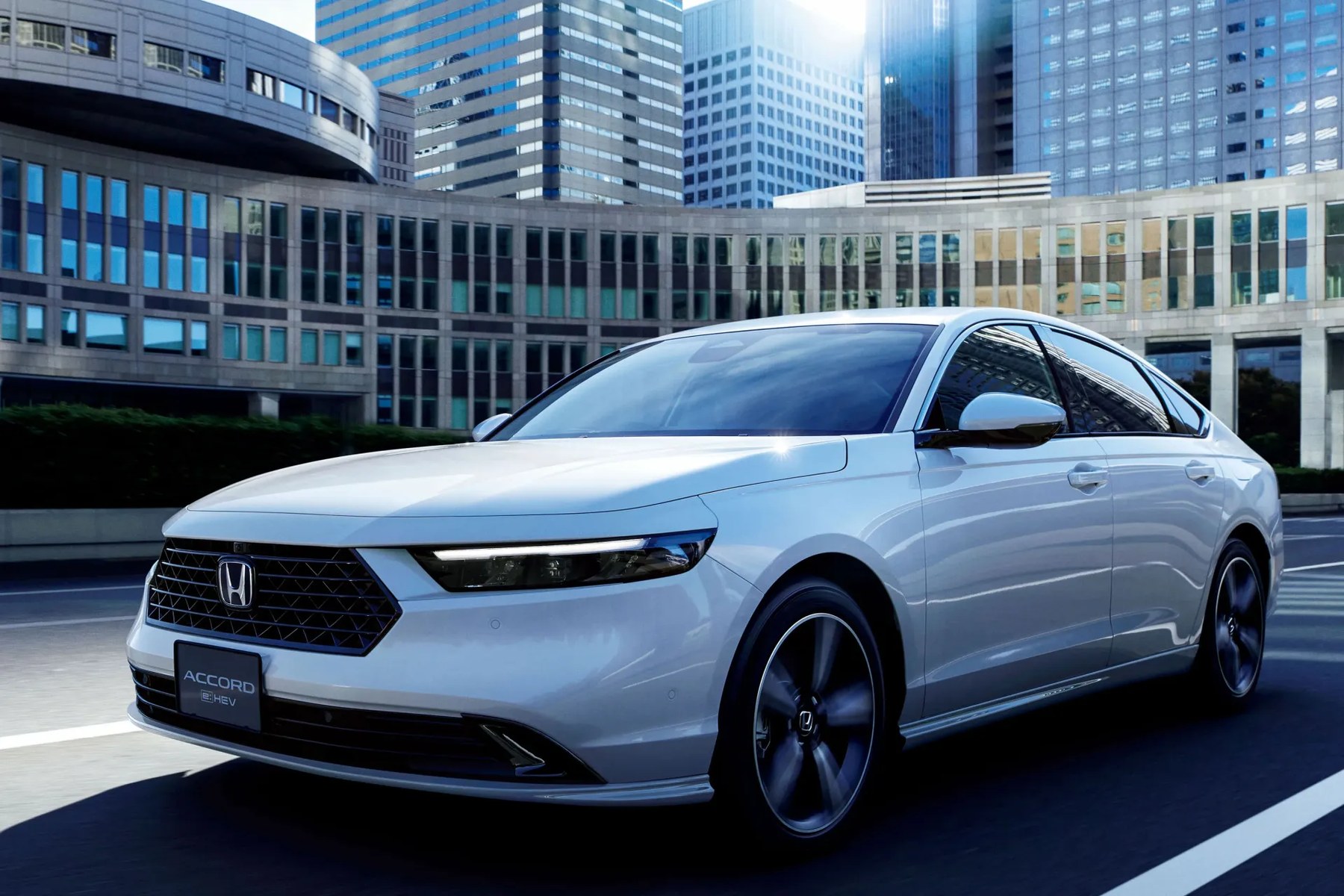 White Honda Accord sedan with black grille and alloy wheels on city street with modern buildings.